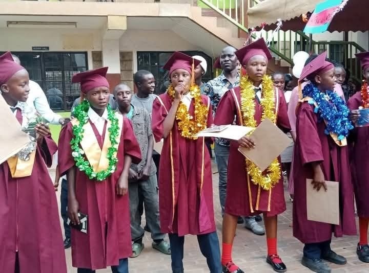Children in graduation caps and gowns with garlands