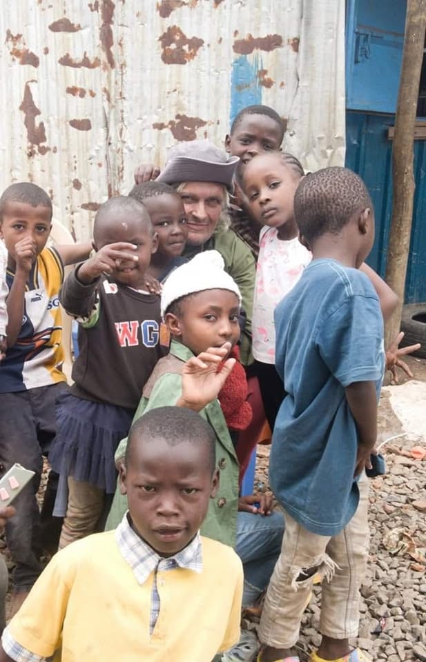 A friend of the centre surrounded by happy children