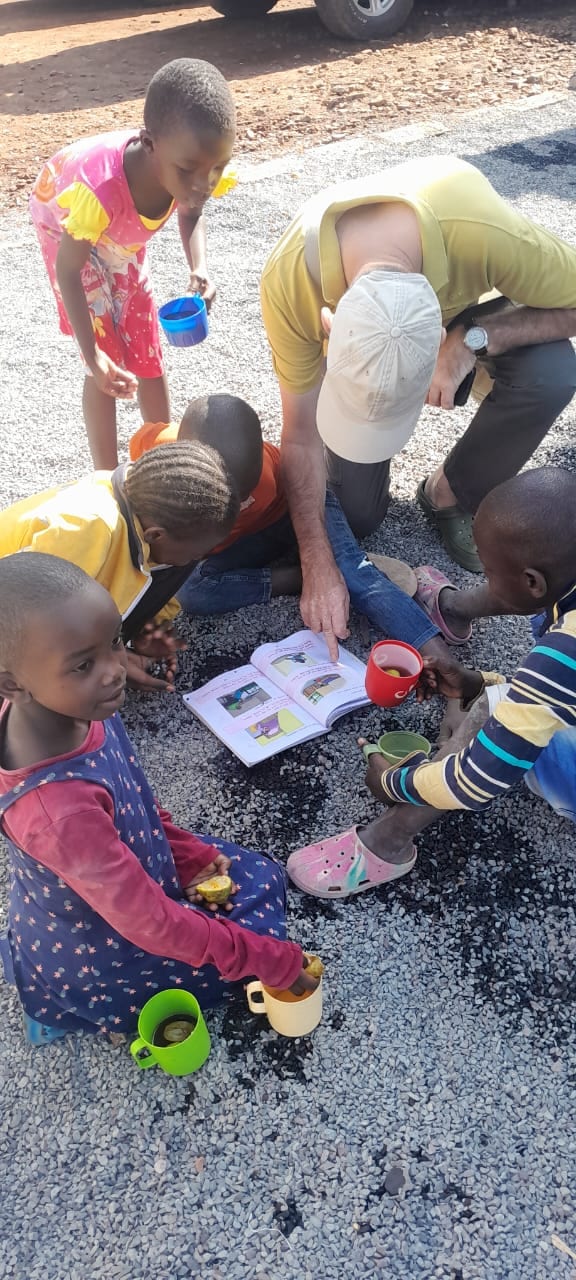 A volunteer reading a storybook with children outdoors