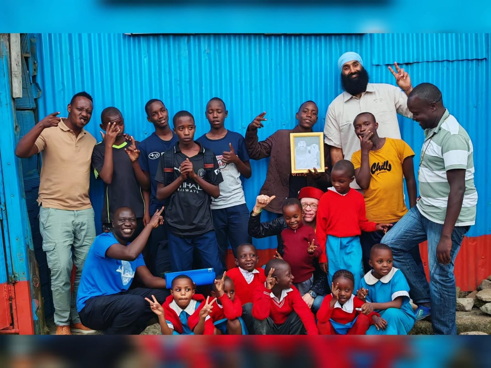 A visiting guest poses with children and staff outside the centre