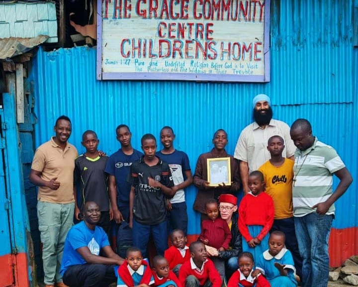 Children and staff gathered outside The Grace Community Centre beneath its sign
