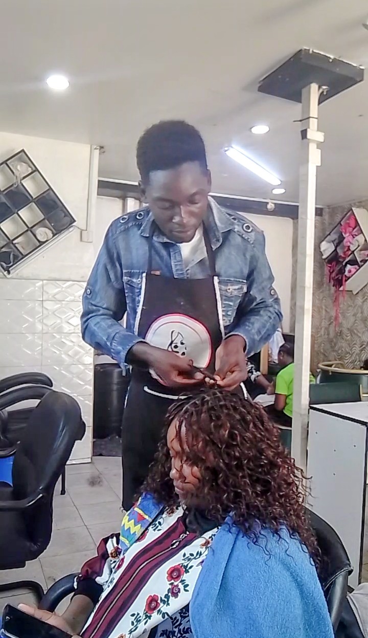 Collo Smile KE styling a client&rsquo;s hair at a salon, a member of The Grace Community Centre community